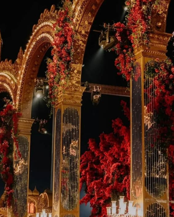 Large outdoor archways decorated with exotic flowers, string lights, spotlights and lamps
